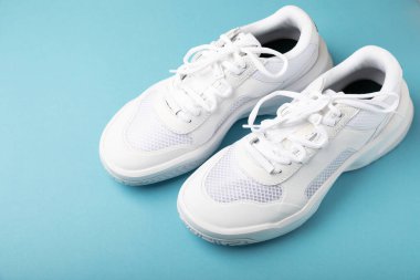 Pair of white shoes on a blue paper background. Sport shoes. Unisex. Street style.