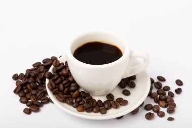 Coffee beans and a cup of stale strong espresso isolated on white background.