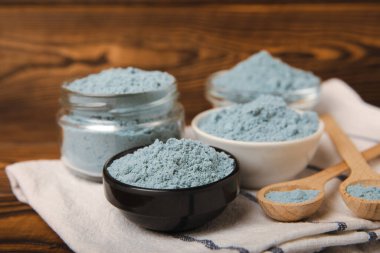 Blue spirulina powder in bowls on a brown table. Natural vegan superfood. Food supplement. Phycocyanin extract. Healthly food. Place for text. Copy space.