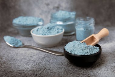 Blue spirulina powder in bowls on black texture background. Natural vegan superfood. Food supplement. Phycocyanin extract. Healthly food. Place for text. Copy space.