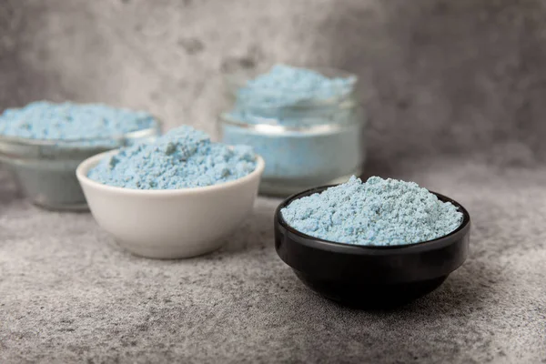 Blue spirulina powder in bowls on black texture background. Natural vegan superfood. Food supplement. Phycocyanin extract. Healthly food. Place for text. Copy space.