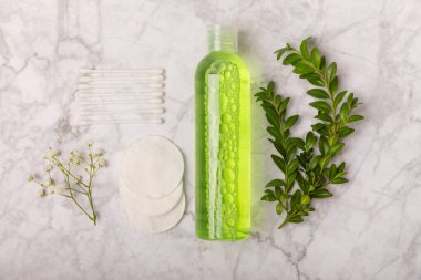 Micellar cleansing water and cotton pads on a marble background. Facial cleansing or makeup remover cosmetic bottle in bathroom. Skin care concepts. Cleansing the face of makeup and skin sebum.