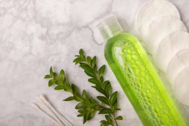 Micellar cleansing water and cotton pads on a marble background. Facial cleansing or makeup remover cosmetic bottle in bathroom. Skin care concepts. Cleansing the face of makeup and skin sebum.