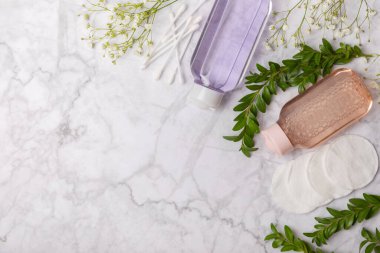 Micellar cleansing water and cotton pads on a marble background. Facial cleansing or makeup remover cosmetic bottle in bathroom. Skin care concepts. Cleansing the face of makeup and skin sebum.