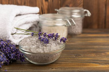 Sea salt with lavender flowers in a bowl on a brown textural background. Bath salt with lavender extract and aroma. Beauty spa treatments. Skin care concept.