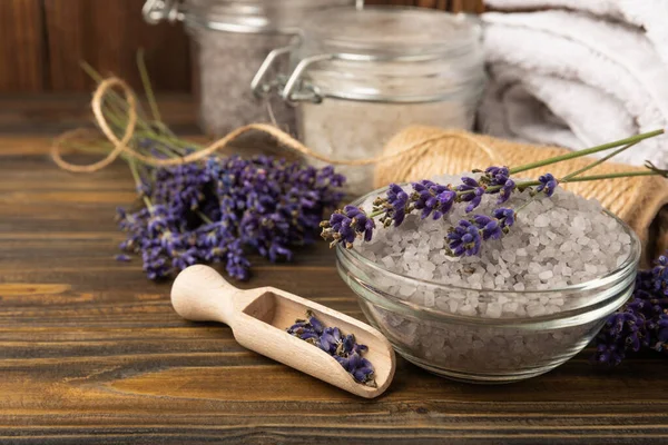 Sea salt with lavender flowers in a bowl on a brown textural background. Bath salt with lavender extract and aroma. Beauty spa treatments. Skin care concept.