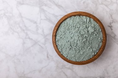 Blue spirulina powder in a bowl on a white marble background. Natural superfood, vegan, healthy food supplement. Phycocyanin extract. Antioxidant. Place for text. Copy space.