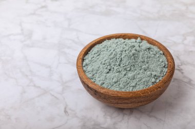 Blue spirulina powder in a bowl on a white marble background. Natural superfood, vegan, healthy food supplement. Phycocyanin extract. Antioxidant. Place for text. Copy space.