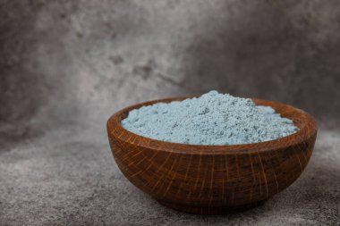 Blue spirulina powder in a bowl on a black marble background. Natural superfood, vegan, healthy food supplement. Phycocyanin extract. Antioxidant. Place for text. Copy space.