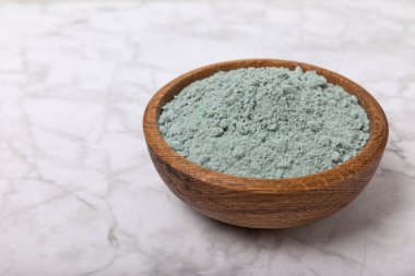 Blue spirulina powder in a bowl on a white marble background. Natural superfood, vegan, healthy food supplement. Phycocyanin extract. Antioxidant. Place for text. Copy space.