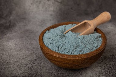 Blue spirulina powder in a bowl on a black marble background. Natural superfood, vegan, healthy food supplement. Phycocyanin extract. Antioxidant. Place for text. Copy space.