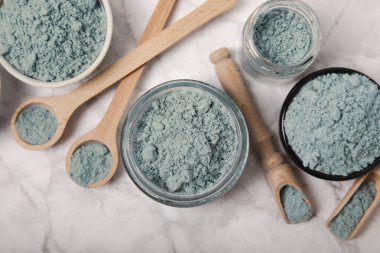 Blue spirulina powder in jars, bowls and spoons on a marble background. Natural superfood, vegan, healthy food supplement. Phycocyanin extract. Antioxidant. Place for text. Copy space.
