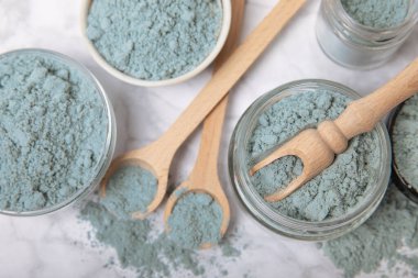 Blue spirulina powder in jars, bowls and spoons on a marble background. Natural superfood, vegan, healthy food supplement. Phycocyanin extract. Antioxidant. Place for text. Copy space.