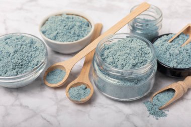 Blue spirulina powder in jars, bowls and spoons on a marble background. Natural superfood, vegan, healthy food supplement. Phycocyanin extract. Antioxidant. Place for text. Copy space.