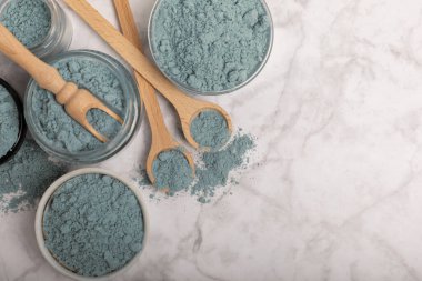 Blue spirulina powder in jars, bowls and spoons on a marble background. Natural superfood, vegan, healthy food supplement. Phycocyanin extract. Antioxidant. Place for text. Copy space.