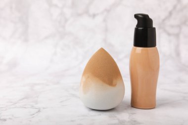 Beauty blender and foundation, bb cream or concealer on marble background. Bright sponges for make-up cosmetics. Makeup products. Beauty concept. Place for text. Place to copy. flat lay