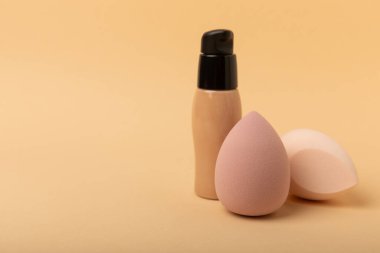 Beauty blender and foundation, bb cream or concealer on a colored background. Bright sponges for make-up cosmetics. Makeup products. Beauty concept. Place for text. Place to copy. flat lay