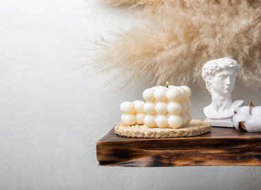 Soy wax bubble candle on a textured table. Interior decor with handmade burning candle and dried flowers. Hygge home decoration concept and aromatherapy.