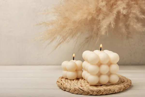 Soy wax bubble candle on a textured table. Interior decor with handmade burning candle and dried flowers. Hygge home decoration concept and aromatherapy.