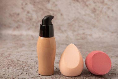 Liquid foundation for makeup and sponge blender for makeup. Foundation beauty face makeup application, perfect makeup tool. Beauty blender,bb cream or concealer on marble texture background.