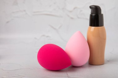 Liquid foundation for makeup and sponge blender for makeup. Foundation beauty face makeup application, perfect makeup tool. Beauty blender,bb cream or concealer on marble texture background.