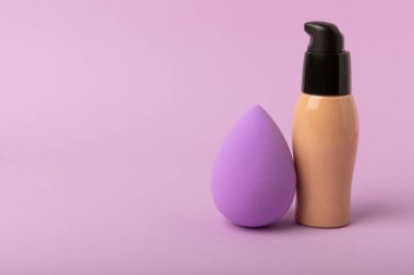 Beauty blender,bb cream or concealer on a colorful bright background.Liquid makeup base and makeup blender sponge. Foundation beauty face makeup application, perfect makeup tool.
