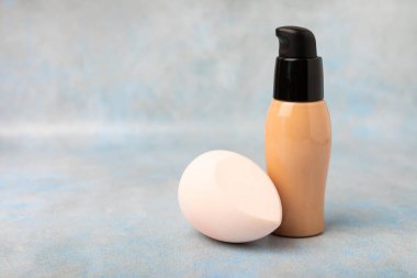 Liquid foundation for makeup and sponge blender for makeup. Foundation beauty face makeup application, perfect makeup tool. Beauty blender,bb cream or concealer on marble texture background.