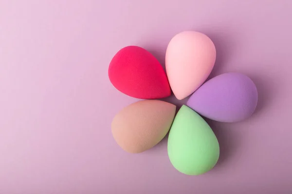 Beauty blender. Colorful beauty sponges on a lilac background. Cosmetic tool for applying foundation, concealer. Place for text. Place to copy.