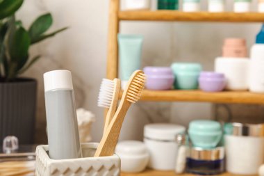 Eco bamboo toothbrushes and toothpaste tube mockup in the bathroom. Toothbrushes on the background of cosmetics on the shelf. Beauty concept. Dental car.