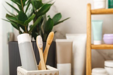 Eco bamboo toothbrushes and toothpaste tube mockup in the bathroom. Toothbrushes on the background of cosmetics on the shelf. Beauty concept. Dental car.