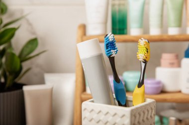 Toothbrushes and mock-up of a tube of toothpaste in a glass in the bathroom. Toothbrushes on the background of cosmetics on the shelf. Beauty concept. Dental car.