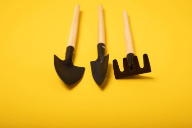 Garden tools on a yellow background. Garden shovel and rake. Items for work in the garden and flower beds. Tools for landscape design and parks.