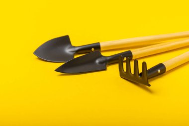 Garden tools on a yellow background. Garden shovel and rake. Items for work in the garden and flower beds. Tools for landscape design and parks.
