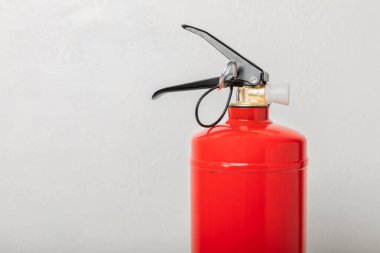 Fire extinguisher on a white wall. Red fire extinguisher indoors on the wall. Fire protection, home fire extinguisher. Mockup, space for text, copy space.