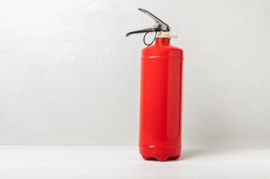 Fire extinguisher on a white wall. Red fire extinguisher indoors on the wall. Fire protection, home fire extinguisher. Mockup, space for text, copy space.