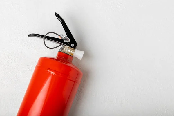 Fire extinguisher on a white wall. Red fire extinguisher indoors on the wall. Fire protection, home fire extinguisher. Mockup, space for text, copy space.