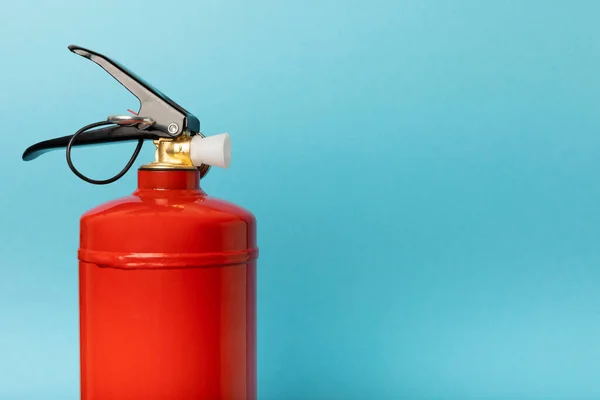 Fire extinguisher on a blue background.Red fire extinguisher indoors on the wall. Fire protection, home fire extinguisher. Mockup, space for text, copy space.