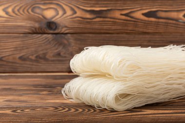 Funchoza.Dried raw rice noodles and rice on a brown wooden background.Noodles with rice flour. Diet food. Healthy food. Place for text. Place for copying.