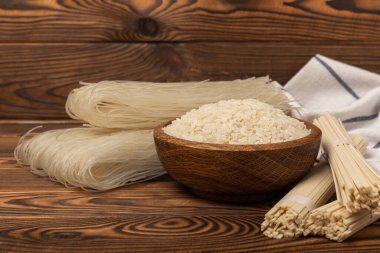 Funchoza.Dried raw rice noodles and rice on a brown wooden background.Noodles with rice flour. Diet food. Healthy food. Place for text. Place for copying.