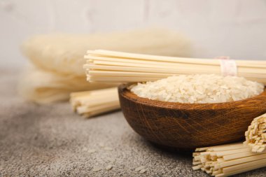 Dried raw rice noodles and rice on a light texture background.Noodles with rice flour. Funchoza. Diet food. Healthy food. Place for text. Place for copying.