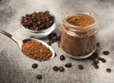 Ingredients for making coffee - coffee beans, ground and instant coffee on a black textured background. Caffeine. Decaffeinated coffee. Aroma energy hot drink. Place for text, space for copy.