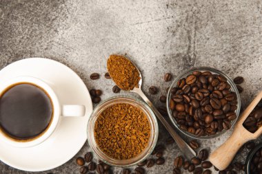 Ingredients for making coffee - coffee beans, ground and instant coffee on a black textured background. Caffeine. Decaffeinated coffee. Aroma energy hot drink. Place for text, space for copy.