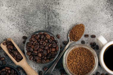 Ingredients for making coffee - coffee beans, ground and instant coffee on a black textured background. Caffeine. Decaffeinated coffee. Aroma energy hot drink. Place for text, space for copy.