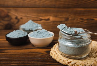 Blue spirulina powder in a bowl, jars and spoons on a brown wooden table. Natural vegan superfood. Healthy food supplement. Phycocyanin extract. Place for text. Place for a copy.