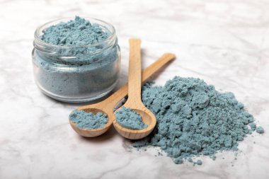 Blue spirulina powder in bowls and spoons on a marble table. Natural vegan superfood. Healthy food supplement. Phycocyanin extract. Place for text. Place for a copy.