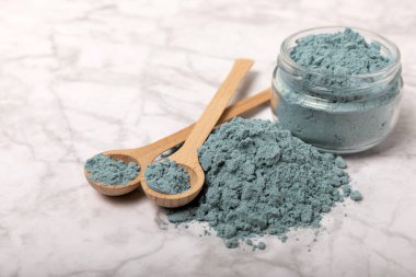 Blue spirulina powder in bowls and spoons on a marble table. Natural vegan superfood. Healthy food supplement. Phycocyanin extract. Place for text. Place for a copy.