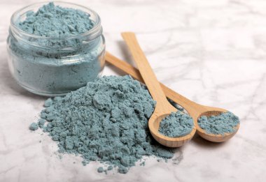Blue spirulina powder in bowls and spoons on a marble table. Natural vegan superfood. Healthy food supplement. Phycocyanin extract. Place for text. Place for a copy.