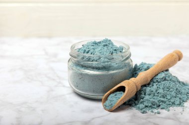 Blue spirulina powder in bowls and spoons on a marble table. Natural vegan superfood. Healthy food supplement. Phycocyanin extract. Place for text. Place for a copy.