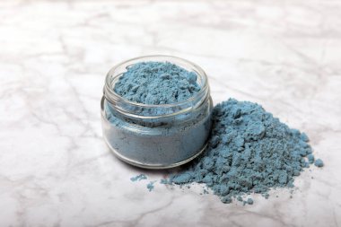 Blue spirulina powder in bowls and spoons on a marble table. Natural vegan superfood. Healthy food supplement. Phycocyanin extract. Place for text. Place for a copy.