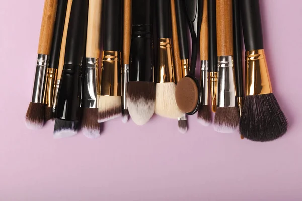 Set of cosmetic brushes on a lilac background. Makeup brushes. Makeup tool. Beauty concept.Professional brushes for applying cosmetics eyeshadows, make-up powder. Place for text. Copy space. Flat lay.